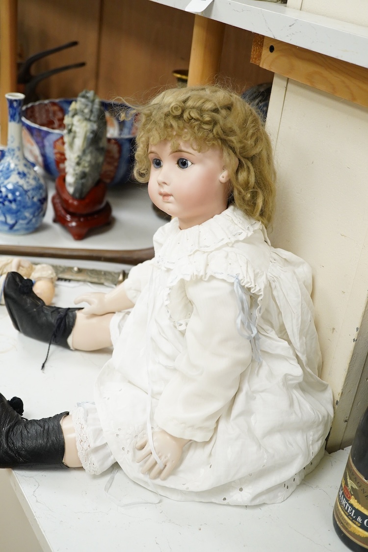 A large jointed bisque head doll and two miniature bisque dolls